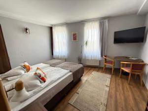 a bedroom with a bed and a table and a television at Lázár Pension & Restaurant in Gheorgheni