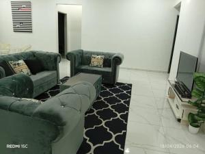 a living room with two green couches and a tv at Hijrah De La Villa Parit Buntar Nibong Tebal Penang in Nibung Tebal