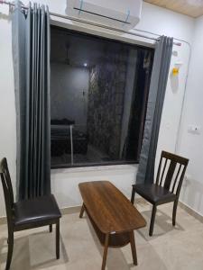 a room with two chairs and a table and a window at Ransuli mountain retreat in Dehradun