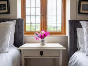 a vase of flowers on a table between two beds at Kingfisher Cottage in Winchcombe