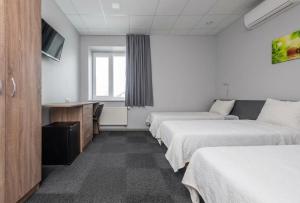 a hotel room with three beds and a desk at Air Kaunas in Karmėlava