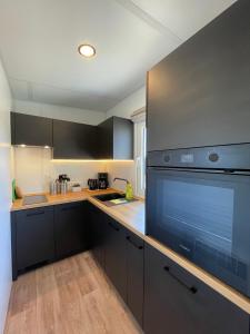 a kitchen with black cabinets and a large appliance at Tinyhaushotel - Campingpark Nabburg in Nabburg