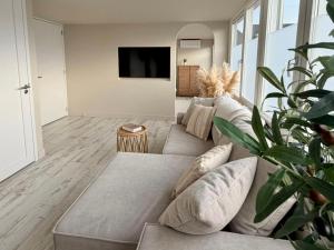 a living room with a couch and a tv at Breeze Inn B&B in Oegstgeest