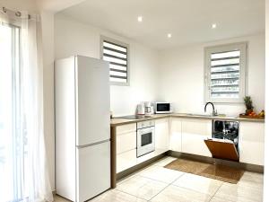 a white kitchen with a refrigerator and a sink at Appartement spacieux La Vanille 2 in Ducos