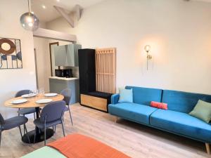 a living room with a blue couch and a table at Le Nid Douillet Studio in Saint-Affrique