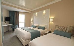 a hotel room with two beds and a television at Sahara Beach Aquapark Resort in Monastir +33 photos