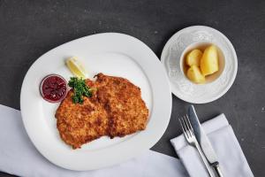 a plate of chicken with a side of fruit and a bowl of sauce at Schloss & Boutique Hotel Mitterhart in Schwaz +123 photos