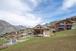 a house on top of a hill with mountains in the background at Tiny Bishorn mit privatem Whirlpool in Grächen