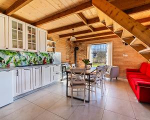 a kitchen and dining room with a table and a red couch at Domki u Danusi z widokiem na wodę in Lipusz
