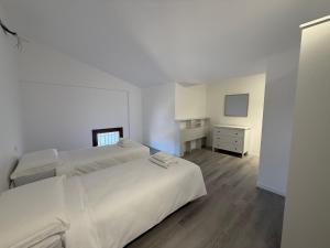 a white bedroom with two beds and a dresser at Country Escape in Poggio Renatico