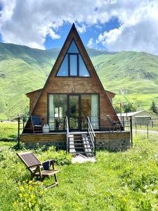 a house with a thatched roof on a grass field at River View Cabin Kazbegi in Kazbegi