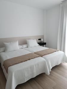 a white bedroom with a large bed with white sheets at Oliva Suite Apartamentos in Pozoblanco