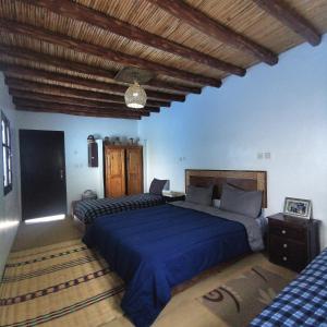 a bedroom with two beds and a wooden ceiling at Dar Lala Zhour in Aïn Bouchrik