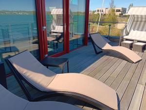 two chairs sitting on a deck with a view of the water at Lagrette Ferienhaus am Hainer See in Neukieritzsch