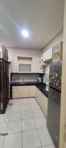 a kitchen with white cabinets and a black refrigerator at CaiPods Backpacker Hostel by G10 Guest House Bandung in Bandung