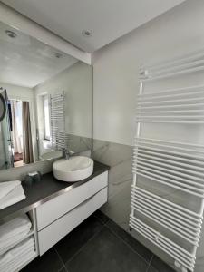 a white bathroom with a sink and a mirror at Strandhotel Sylt Wenningstedt in Wenningstedt +25 photos