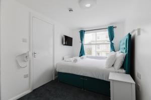 a bedroom with a bed with blue curtains and a window at Whiteleys Hotel in London
