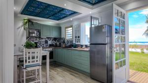 a kitchen with green cabinets and a refrigerator at La Villa Bleue, Pieds dans l'eau in Saint-Leu +12 photos