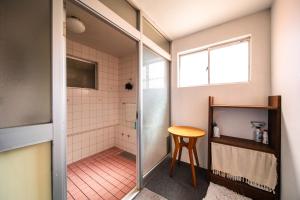 a bathroom with a shower with a table and a stool at The Bears Lodge in Hakuba +64 photos