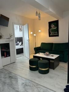 a living room with a green couch and a table at Andra Rezidence in Popeşti-Leordeni
