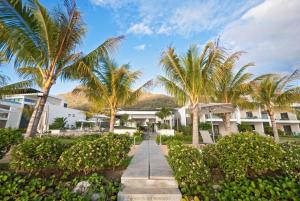 a walkway in front of a resort with palm trees at Latitude - with private plunge pool in Rivière Noire