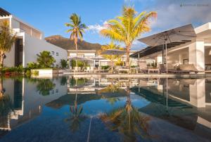 a swimming pool with palm trees and a building at Latitude - with private plunge pool in Rivière Noire