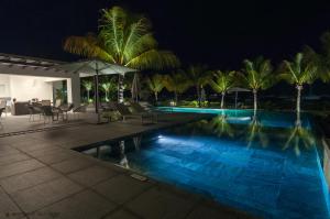 a swimming pool at night with palm trees at Latitude - with private plunge pool in Rivière Noire