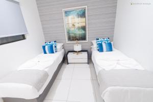 two beds in a white room with blue pillows at Latitude - with private plunge pool in Rivière Noire