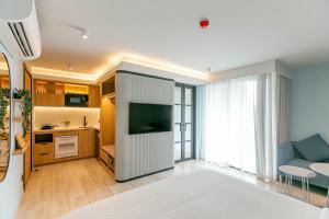 a living room with a couch and a tv in a room at The SACHA Apart-Hotel Thonglor Sukhumvit Bangkok in Bangkok