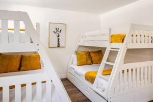 two white bunk beds in a room with yellow pillows at Malibu Beachfront Home with Rock Spa Ocean Views & Huge Deck in Malibu