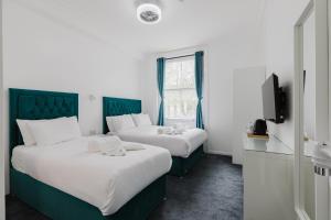 two beds in a hotel room with white and green at Whiteleys Hotel in London
