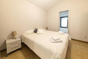 a bedroom with a white bed and a window at Sardinian Gallery S'Iscola in Bosa