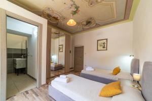 a bedroom with two beds and a mirror at Sardinian Gallery Sa Funtana in Bosa