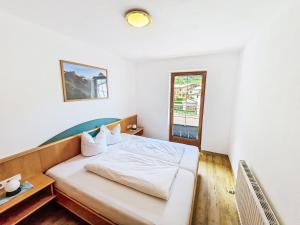 a bedroom with a bed with white sheets and a window at Apartment Handle-3 by Interhome in Ried im Oberinntal