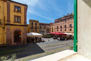 a group of buildings with tables and umbrellas in a street at Sardinian Gallery Sa Funtana in Bosa