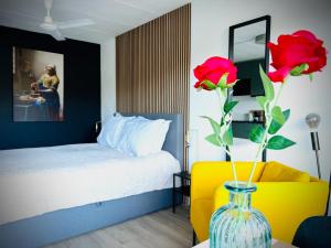 a bedroom with a bed and a vase with red roses at Flamingo Studio's Zeeland in Schoondijke