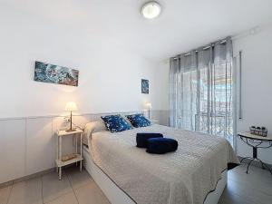 a white bedroom with a large bed with blue pillows at Apartment Pattaya-8 by Interhome in Empuriabrava