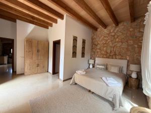a bedroom with a bed and a stone wall at Finca Latenéa in Islas Baleares