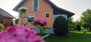 a house with pink flowers in front of it at Holiday Home Vuković Plitvice Mountain Retreat in Saborsko