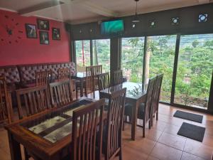 a dining room with tables and chairs and windows at The Green County Homestay in Panglipurgalin +19 photos