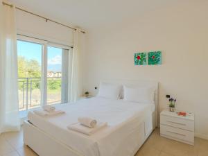 a white bedroom with a large bed and a window at Apartment Sole e Fiori by Interhome in Domaso
