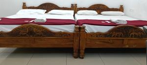 a wooden bed with red and white sheets and pillows at Beach Times Resort in Kottakupam