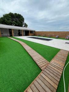 a garden with green grass and a wooden walkway at Sonho Meu in Saquarema