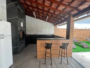 a kitchen with a counter and two stools at a bar at Sonho Meu in Saquarema