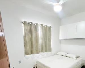 a white room with two beds and a curtain at Sonho Meu in Saquarema