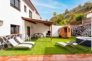 a patio with grass and chairs and a pool at Eden Rentals Villa Marysol in Sauzal +64 photos