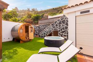 a patio with a chair and a tub on a lawn at Eden Rentals Villa Marysol in Sauzal