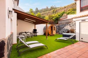 a patio with green grass and chairs on it at Eden Rentals Villa Marysol in Sauzal