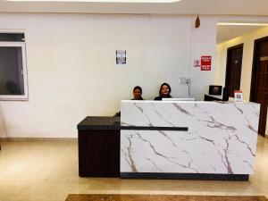 two people sitting at a counter in an office at Hotel shivay palace in Rishīkesh