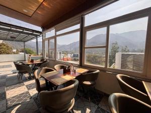 a restaurant with tables and chairs and large windows at Hotel shivay palace in Rishīkesh